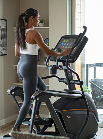 
                        
                         Woman using an elliptical machine in a home setting.
                        
                        